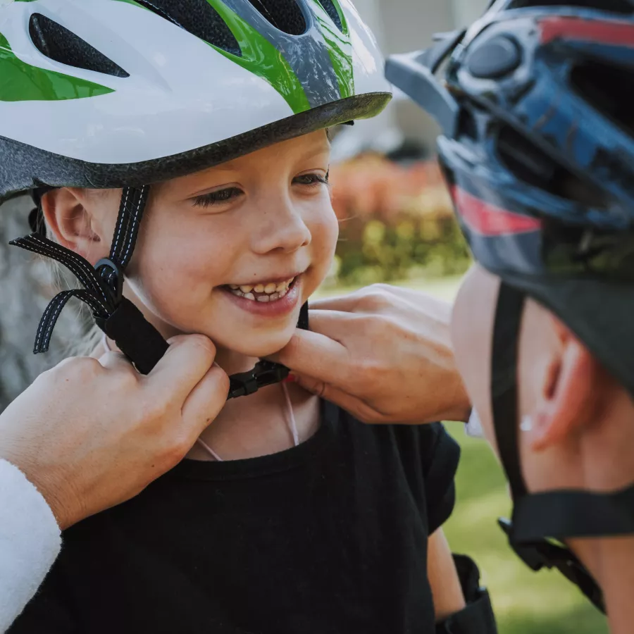 Parent adjusts a child's bike helmet