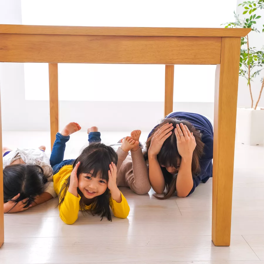 a family practices taking cover under a table
