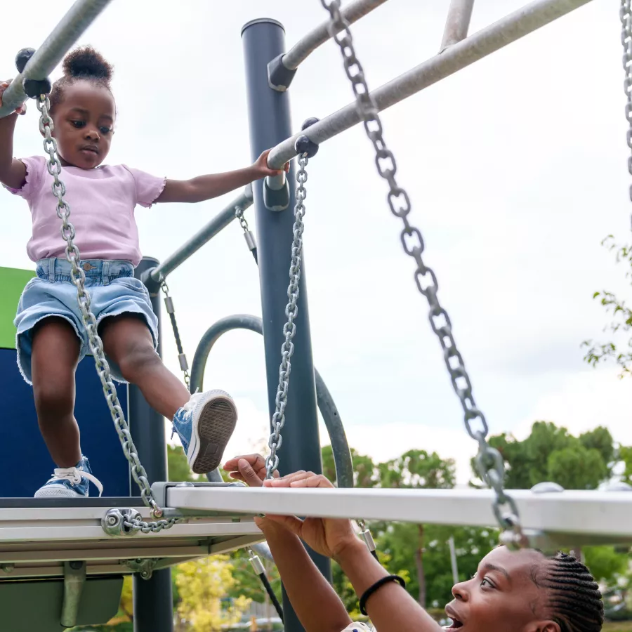 Parent encouraging a child on a climbing structure