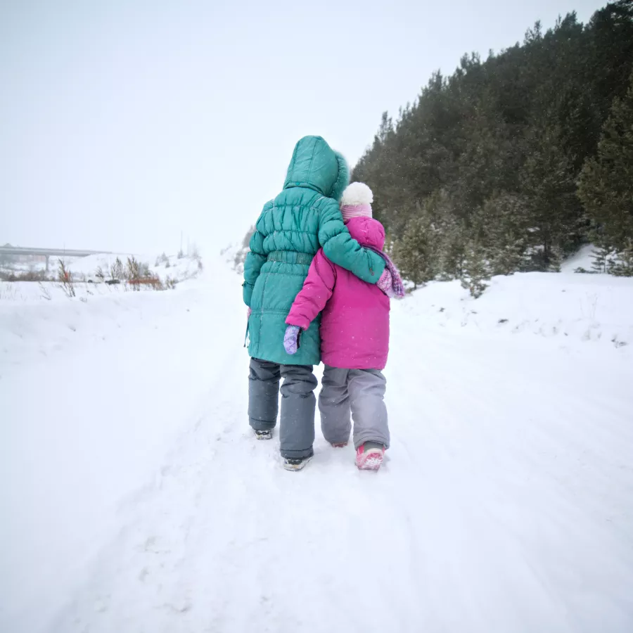 2 children walking in the snow